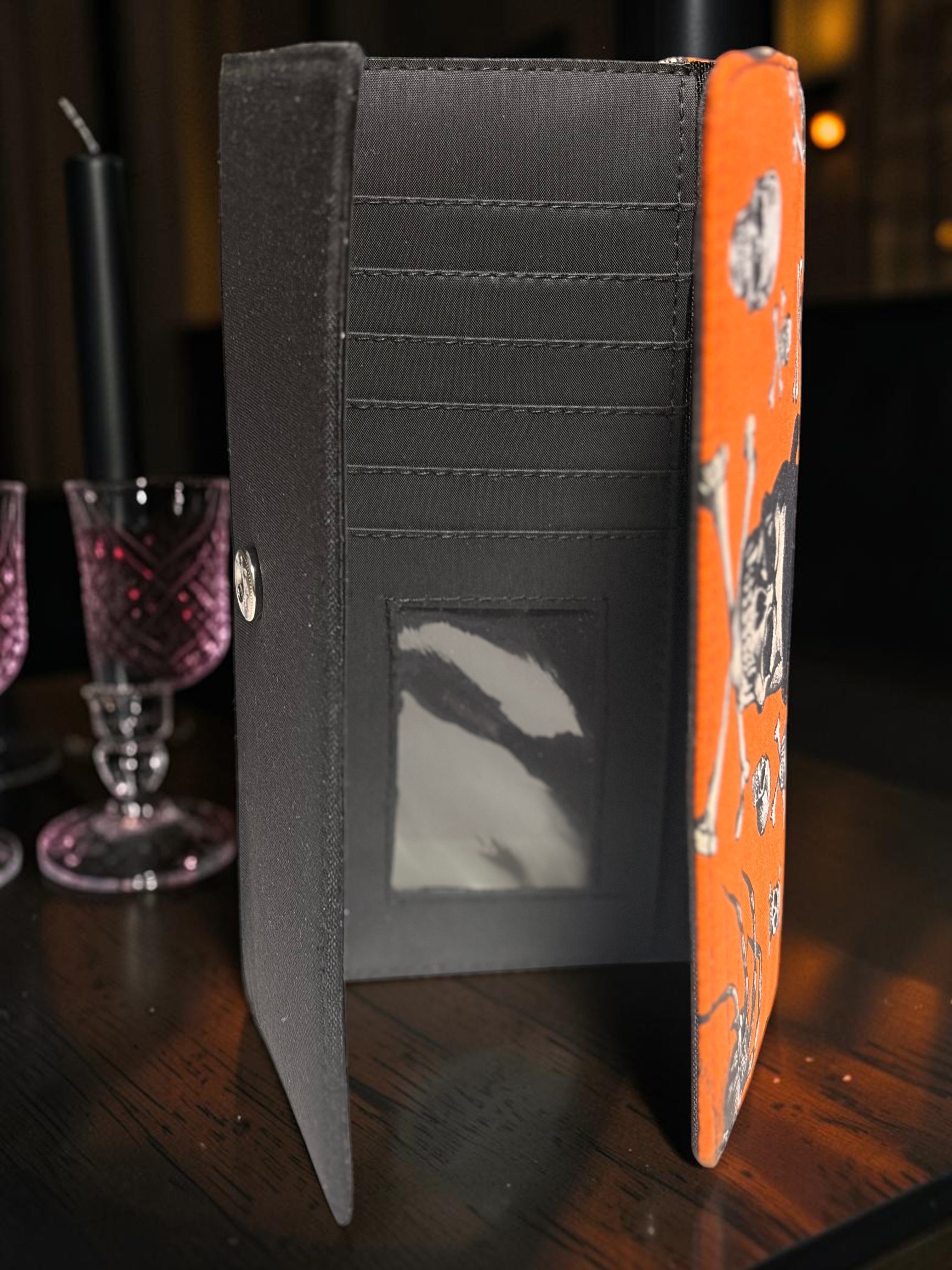 Halloween-Emporium gothic clutch wallet with orange skull and top hat print, featuring card slots and cash pockets.
