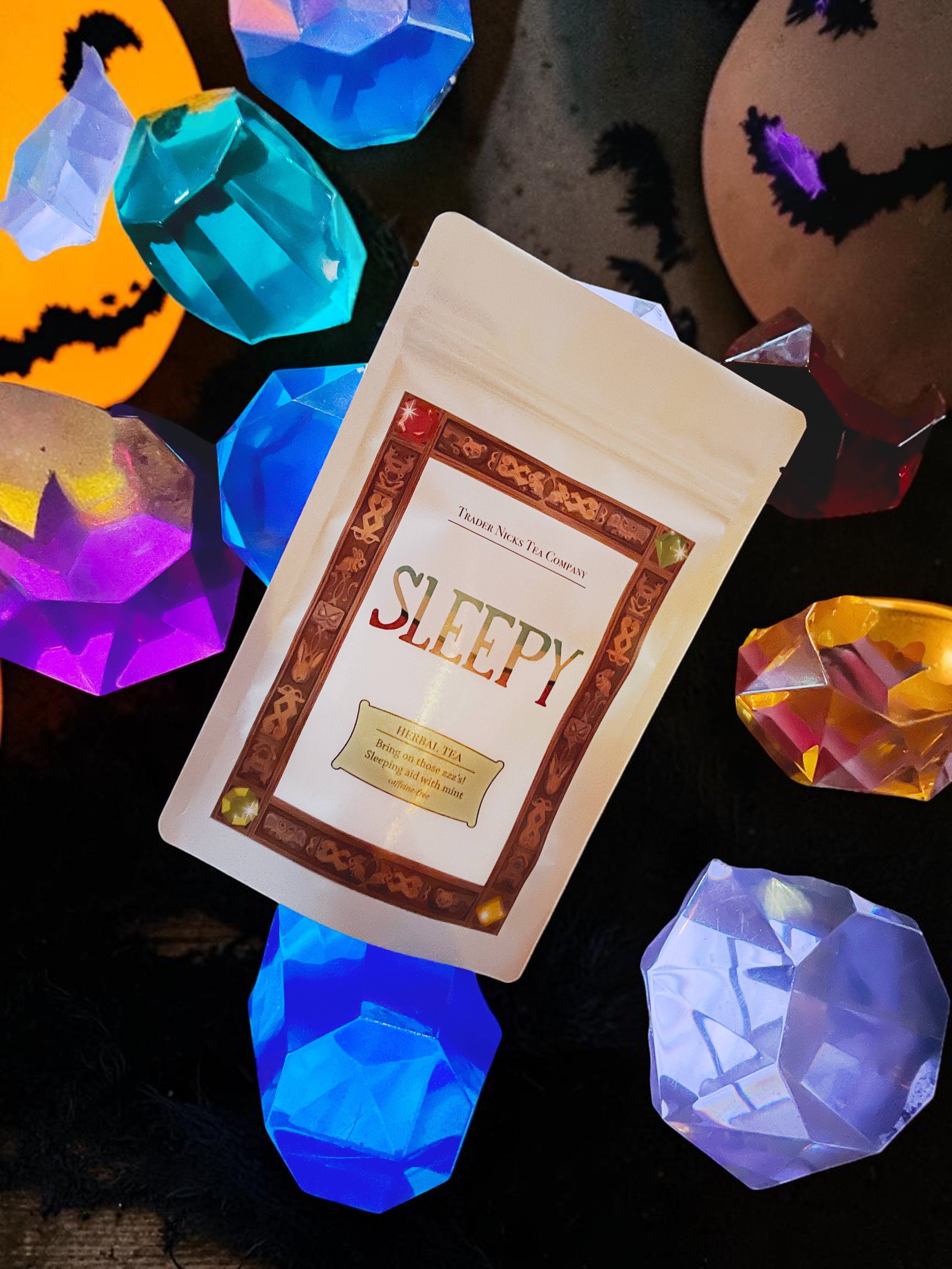Halloween-Emporium Sleepy Wellness herbal tea pouch surrounded by colorful glowing crystal-shaped decorations.