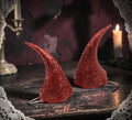 Halloween-Emporium sparkling red glitter devil horns for costume parties on a dark wooden table with candlelight
