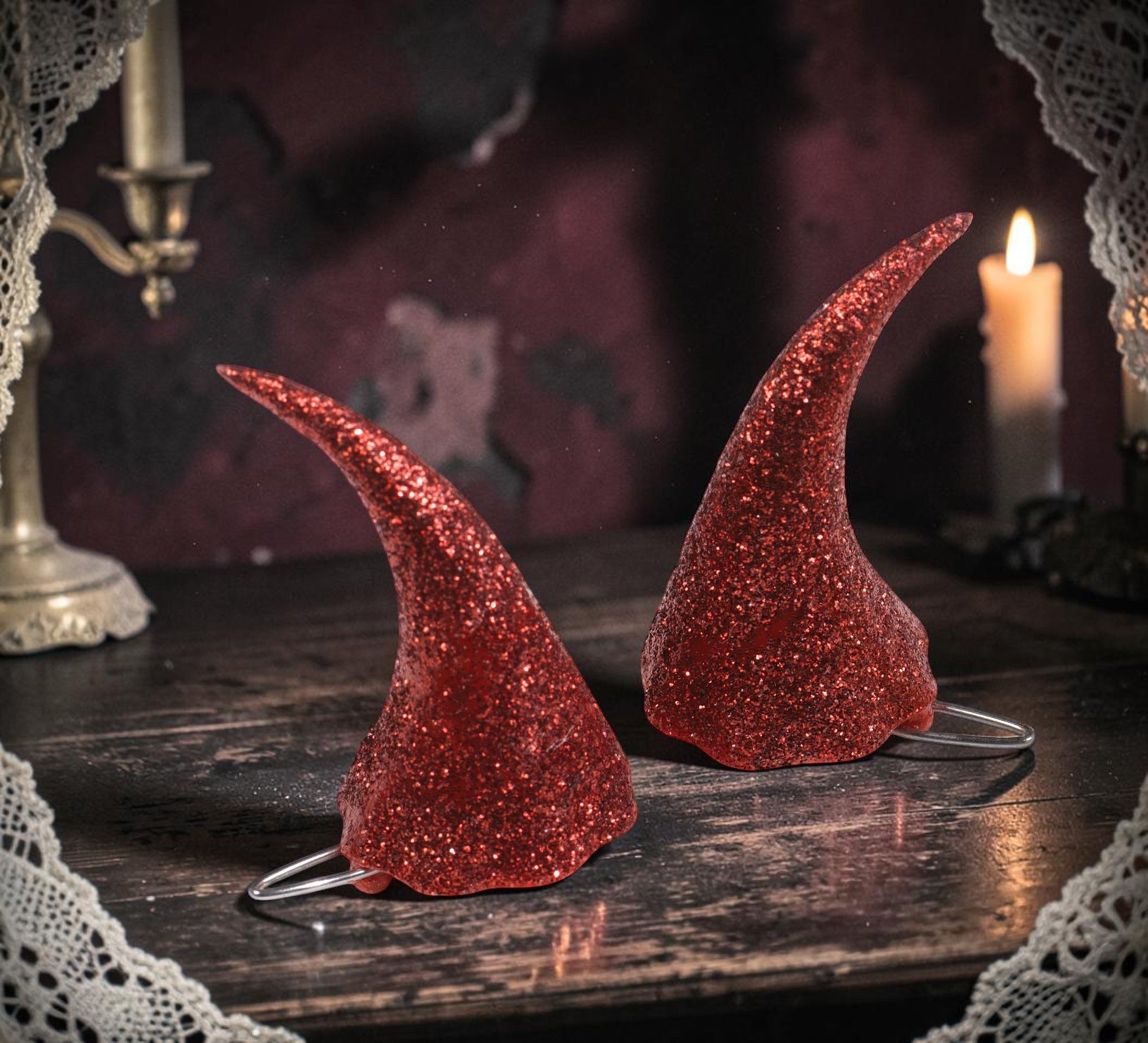 Halloween-Emporium sparkling red glitter devil horns for costume parties on a dark wooden table with candlelight