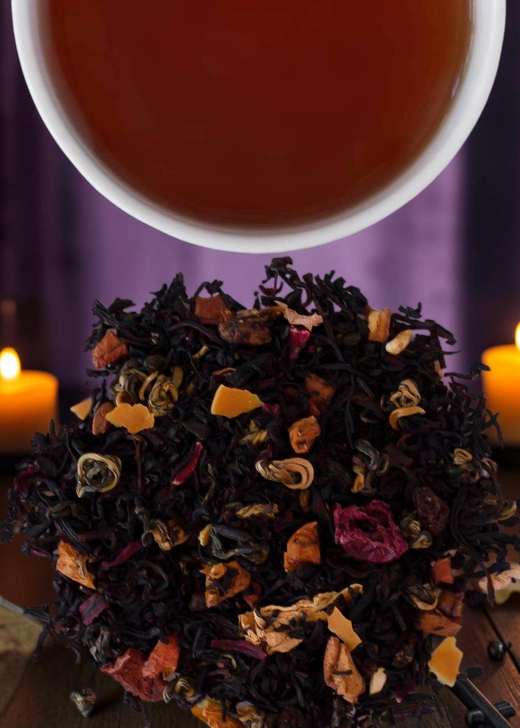 Halloween-Emporium Evil Queen Spiced Apple black tea blend with fruit pieces and black snail tea leaves near candles