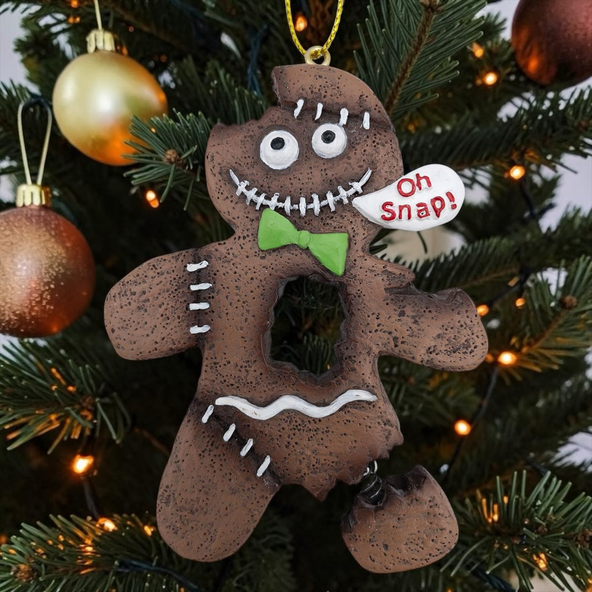 Halloween-Emporium spooky gingerbread man ornament with a green bow tie and Oh Snap speech bubble on a Christmas tree.