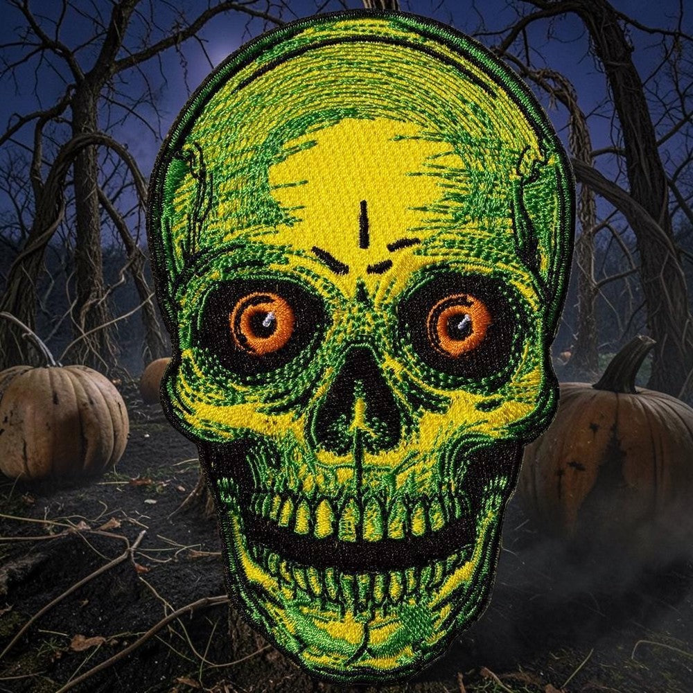 Halloween-Emporium embroidered iron-on patch featuring a neon yellow and green skull with piercing orange eyes.