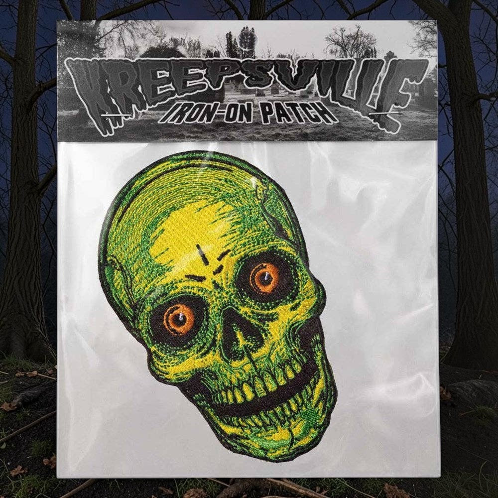 Halloween-Emporium Staring Skull embroidered iron-on patch in neon yellow and green with piercing orange eyes.
