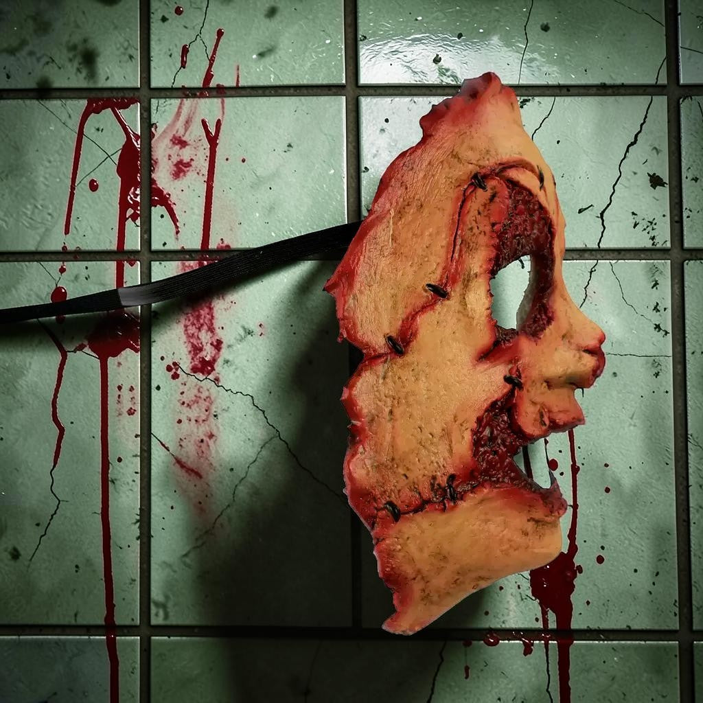 Halloween-Emporium creepy stitched latex serial killer mask with realistic gore detail on a blood-splattered tile wall