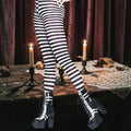 Halloween-Emporium black and white horizontal striped costume leggings worn with platform boots in a spooky setting