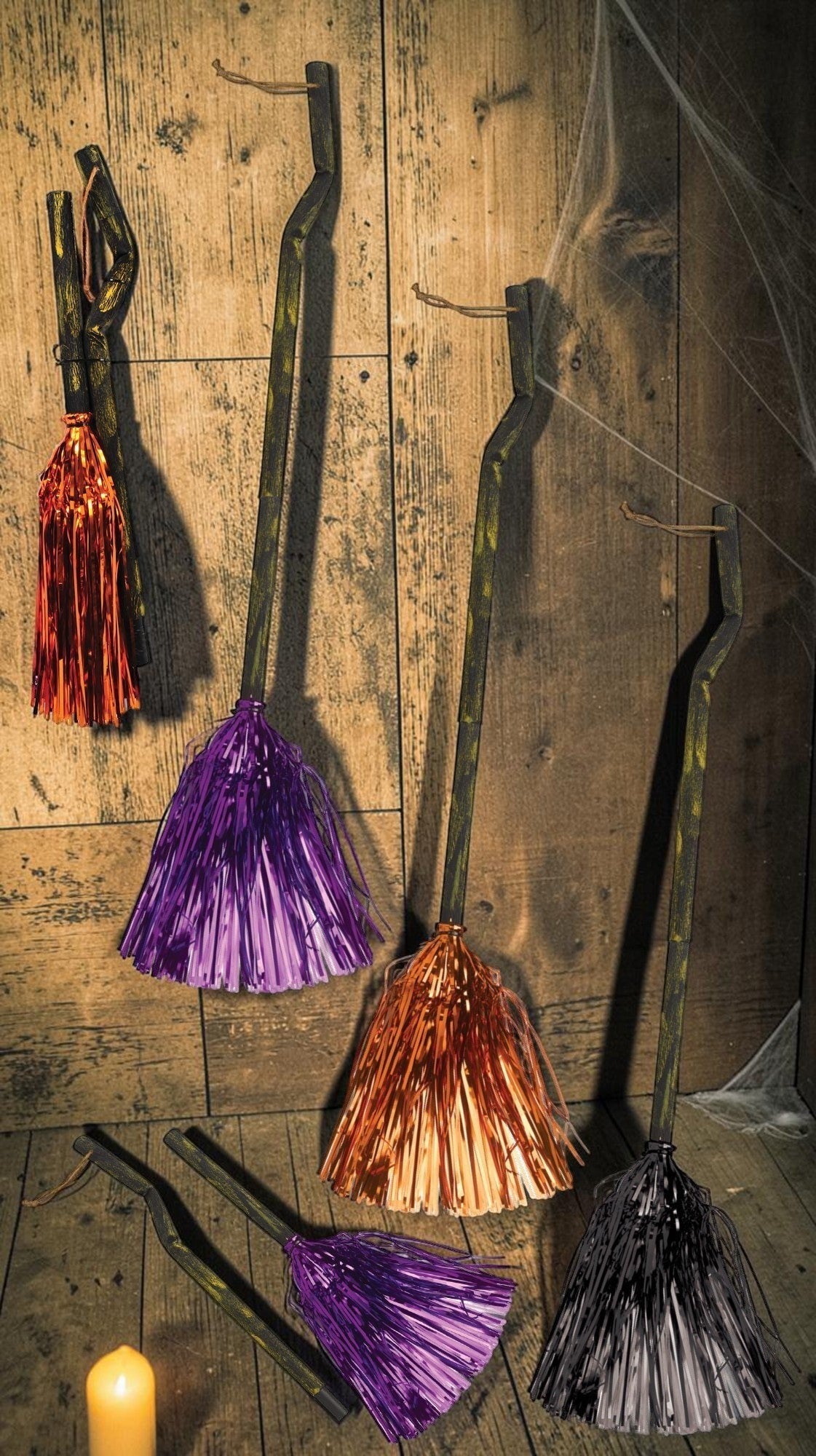 Halloween-Emporium decorative witch broomsticks with rustic gnarled handles and shimmering tinsel bristles in assorted colors