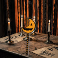 Halloween-Emporium Trick 'r Treat cinnamon-scented pumpkin lollipop air freshener hanging on a rustic wooden table.