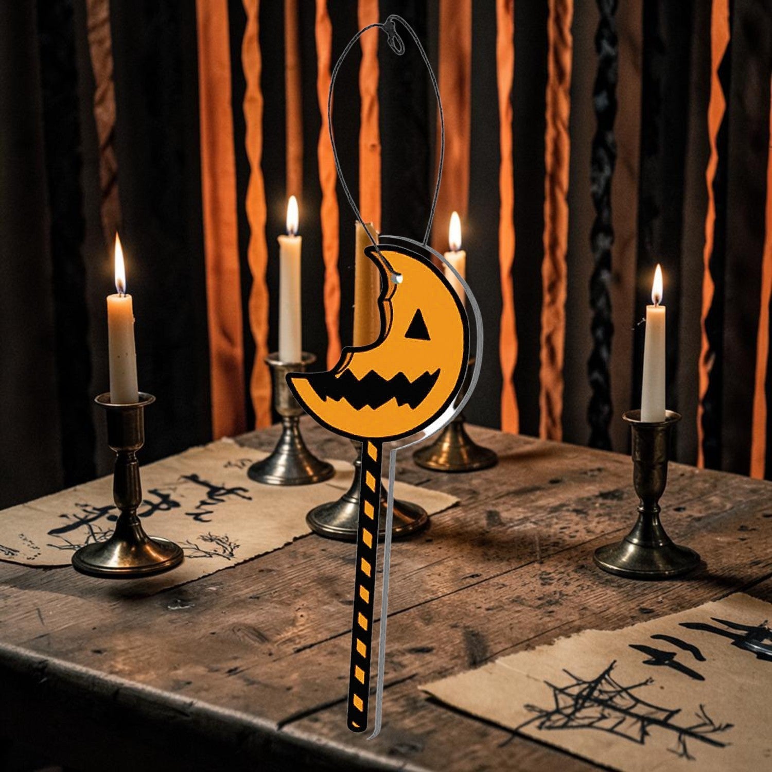 Halloween-Emporium Trick 'r Treat cinnamon-scented pumpkin lollipop air freshener hanging on a rustic wooden table.