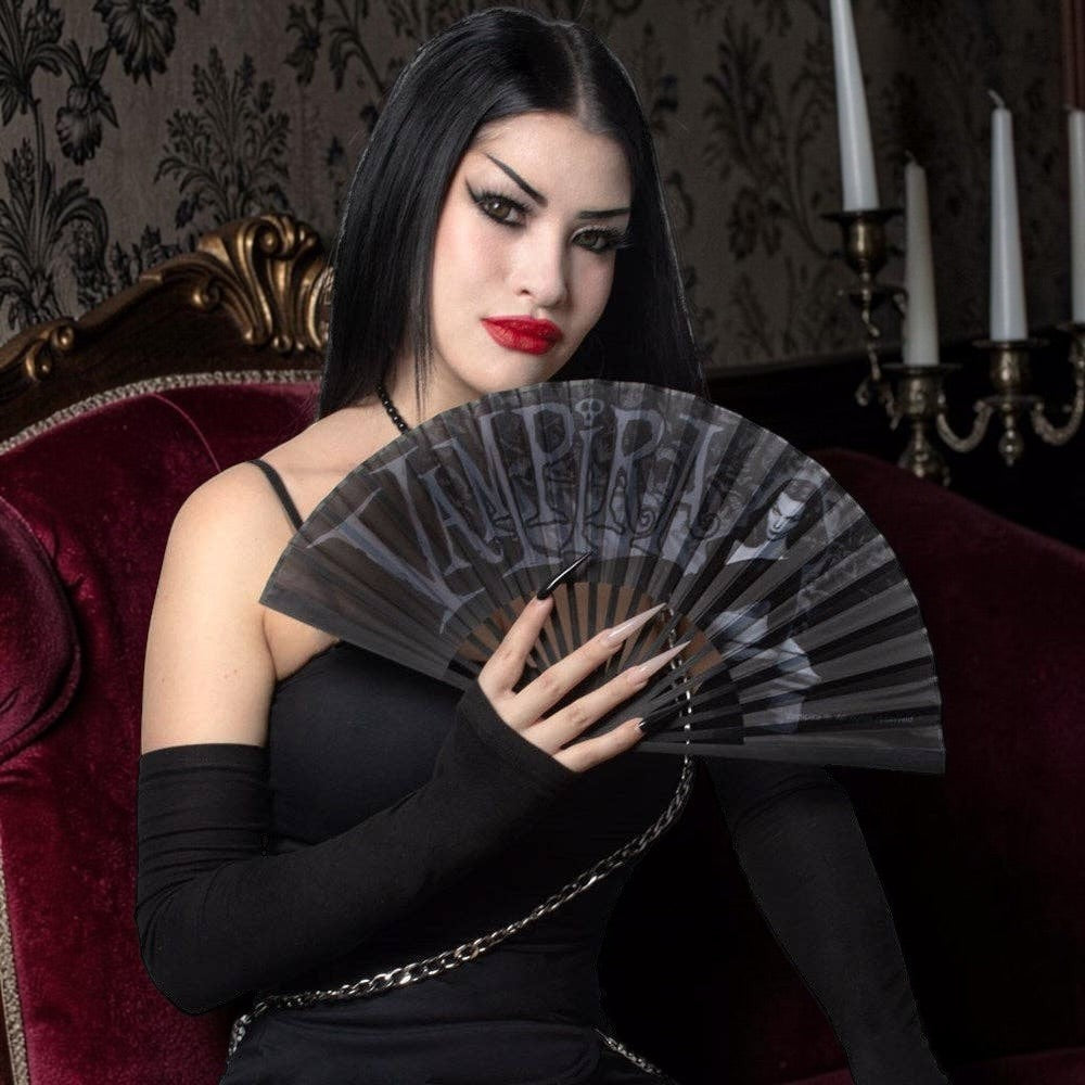 Halloween-Emporium Vampira gothic folding hand fan with portrait and stylized lettering held by a woman in black.