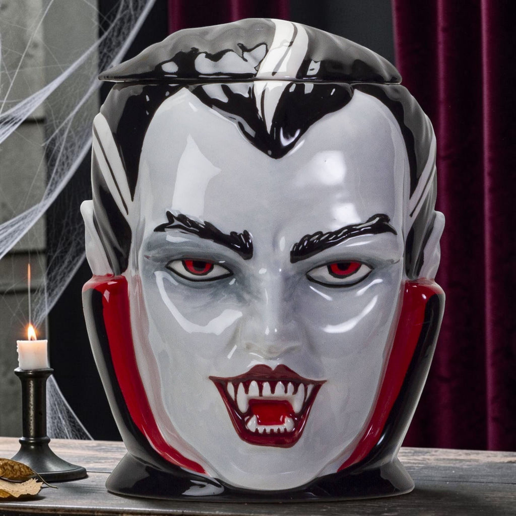 Halloween-Emporium vampire ceramic treat jar with red eyes, sharp fangs, and a glossy black and white finish.