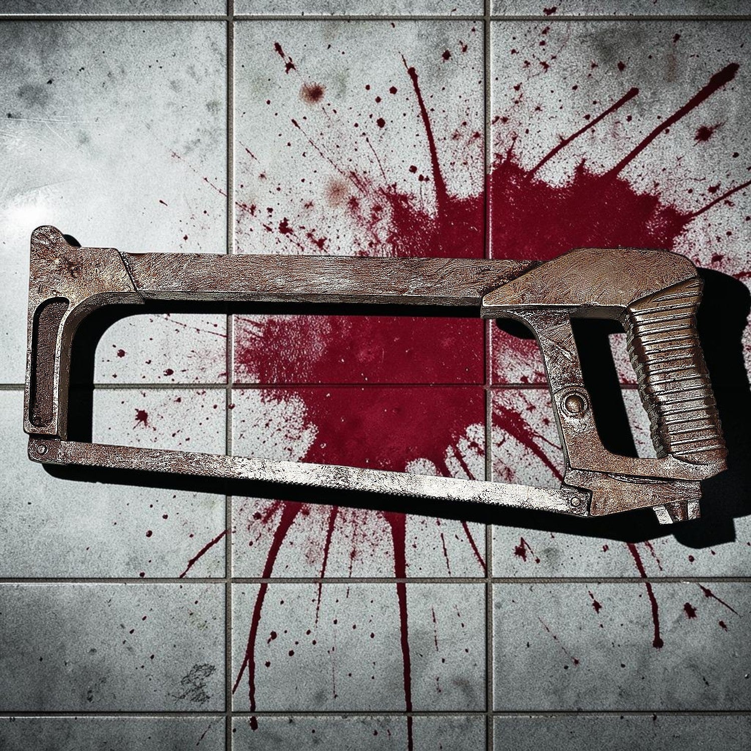 Halloween-Emporium weathered plastic hacksaw prop with a rusted finish, displayed on a blood-splattered tile floor.