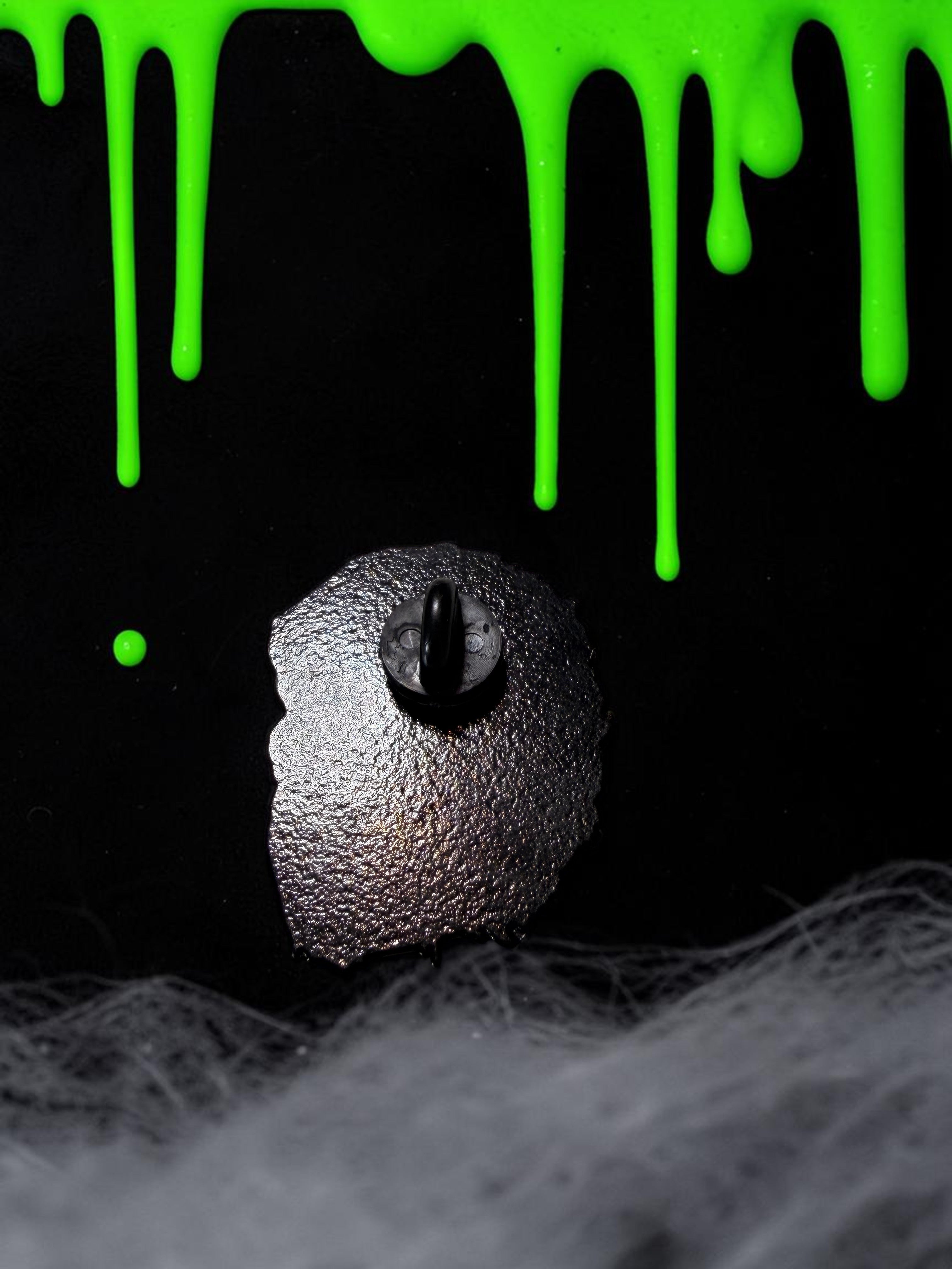 Halloween-Emporium werewolf enamel pin back view showing the secure rubber clutch on a textured black metal surface