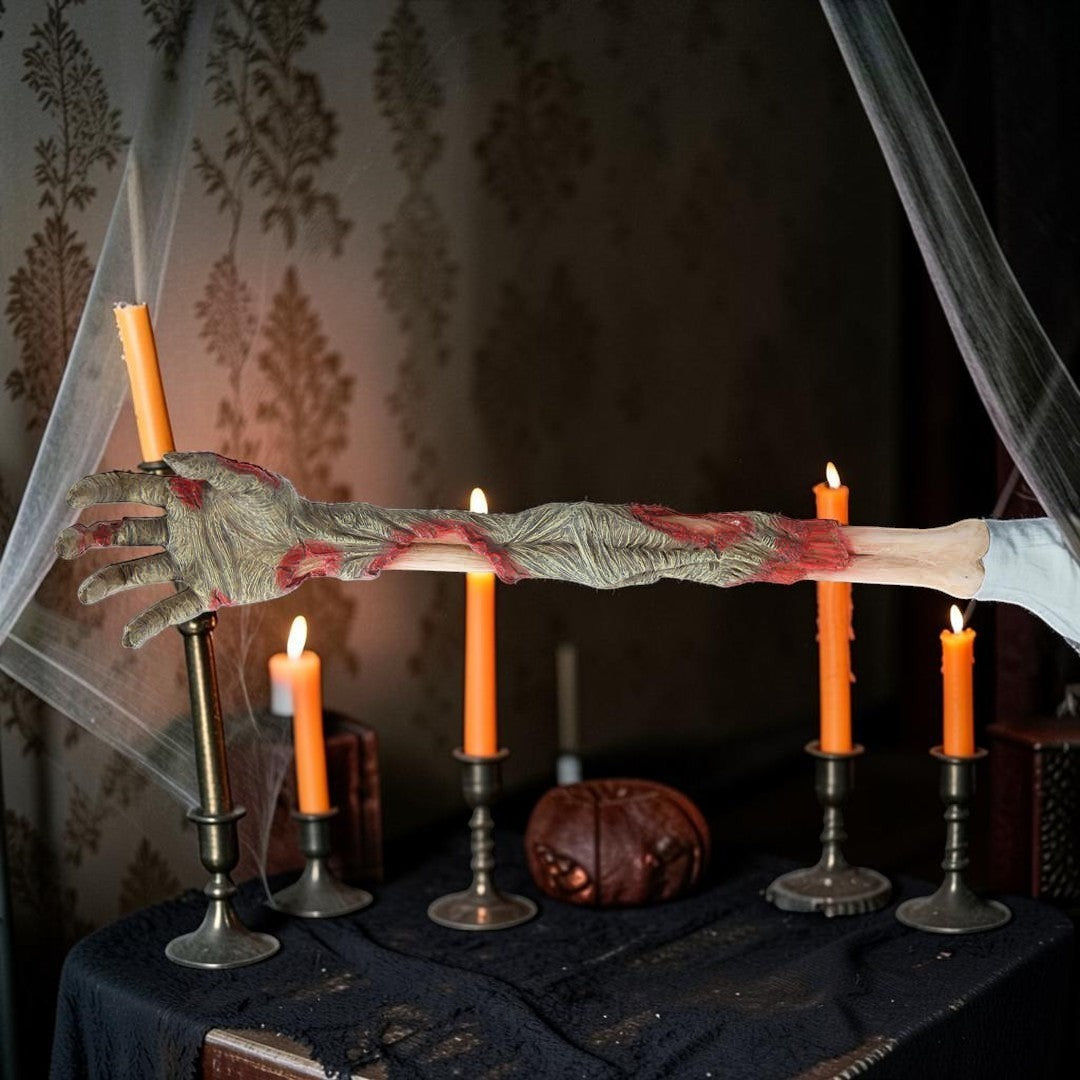 Halloween-Emporium severed zombie arm back scratcher with realistic decaying skin and blood details on a candlelit table