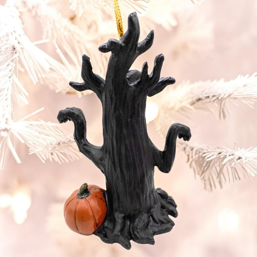 Halloween-Emporium black gnarled tree ornament with a small orange jack-o-lantern hanging on a white tree branch.