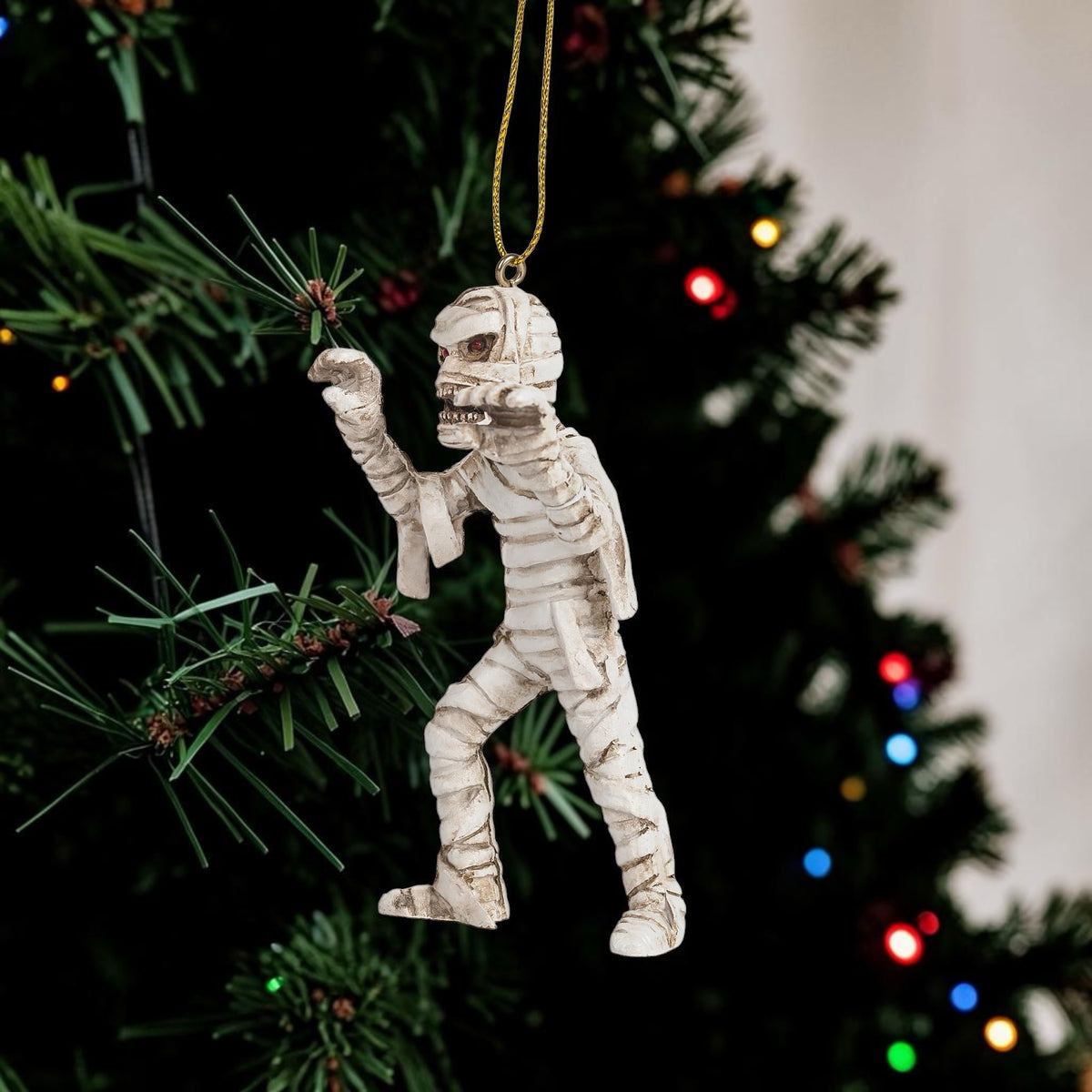 Halloween-Emporium mummy hanging ornament with detailed bandages and menacing expression on a Christmas tree.